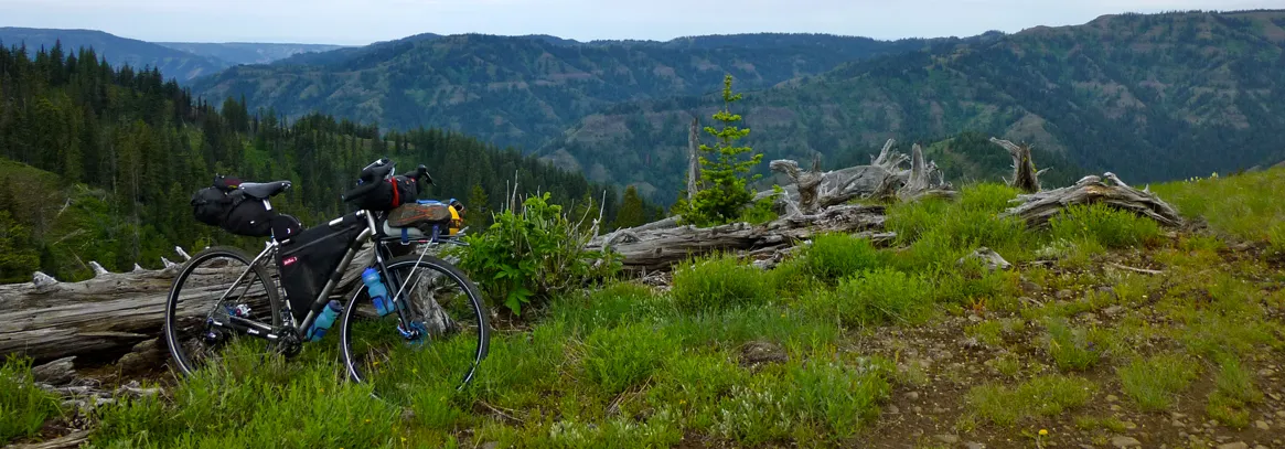 Bicicleta equipada para bikepacking frente a un valle con cerros